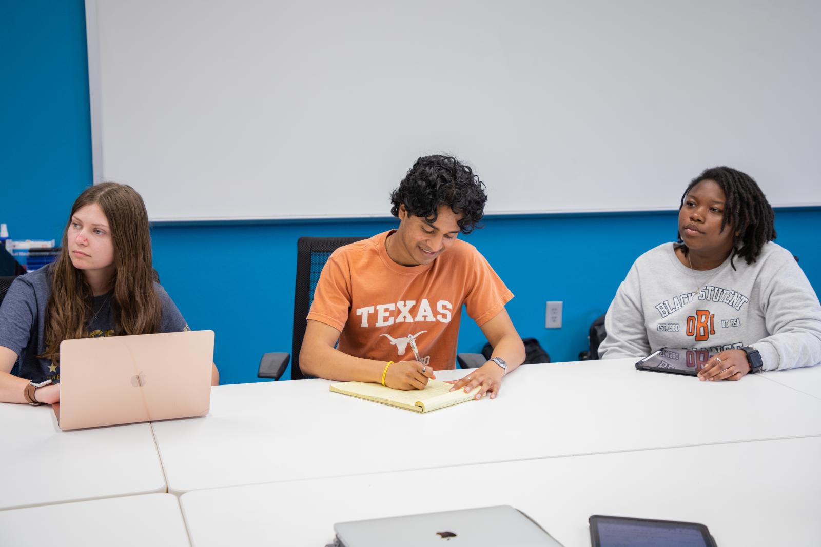 Three students studying, taking notes