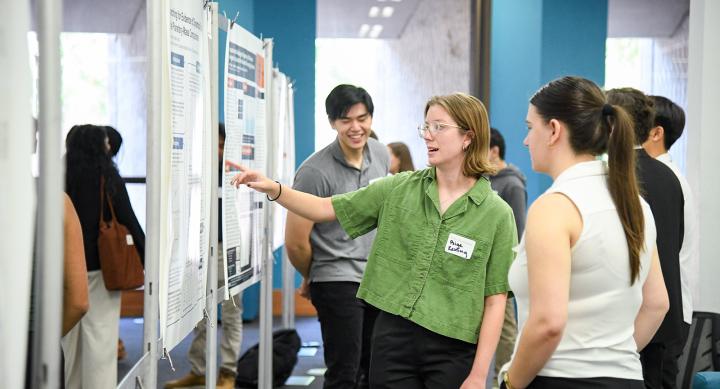 Student at the Longhorn poster session describing their poster and reseach