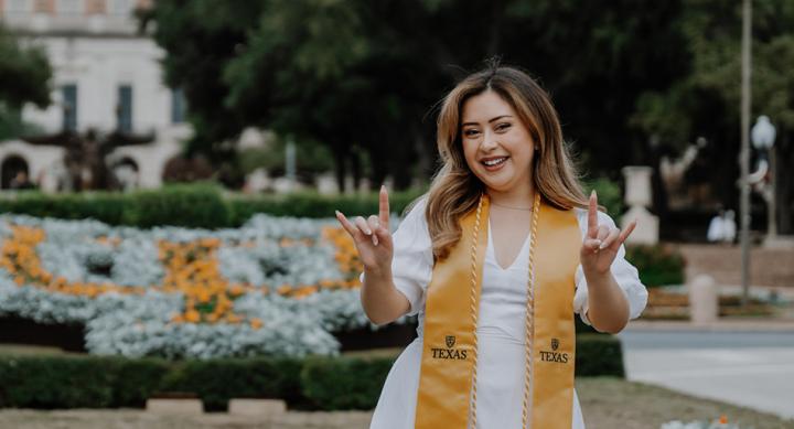 Kristel Holguin poses for her graduation photos, wearing a stole from her college at UT Austin.