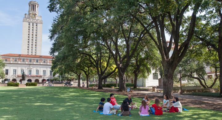 Students sitting in circle on lawn in front of UT tower